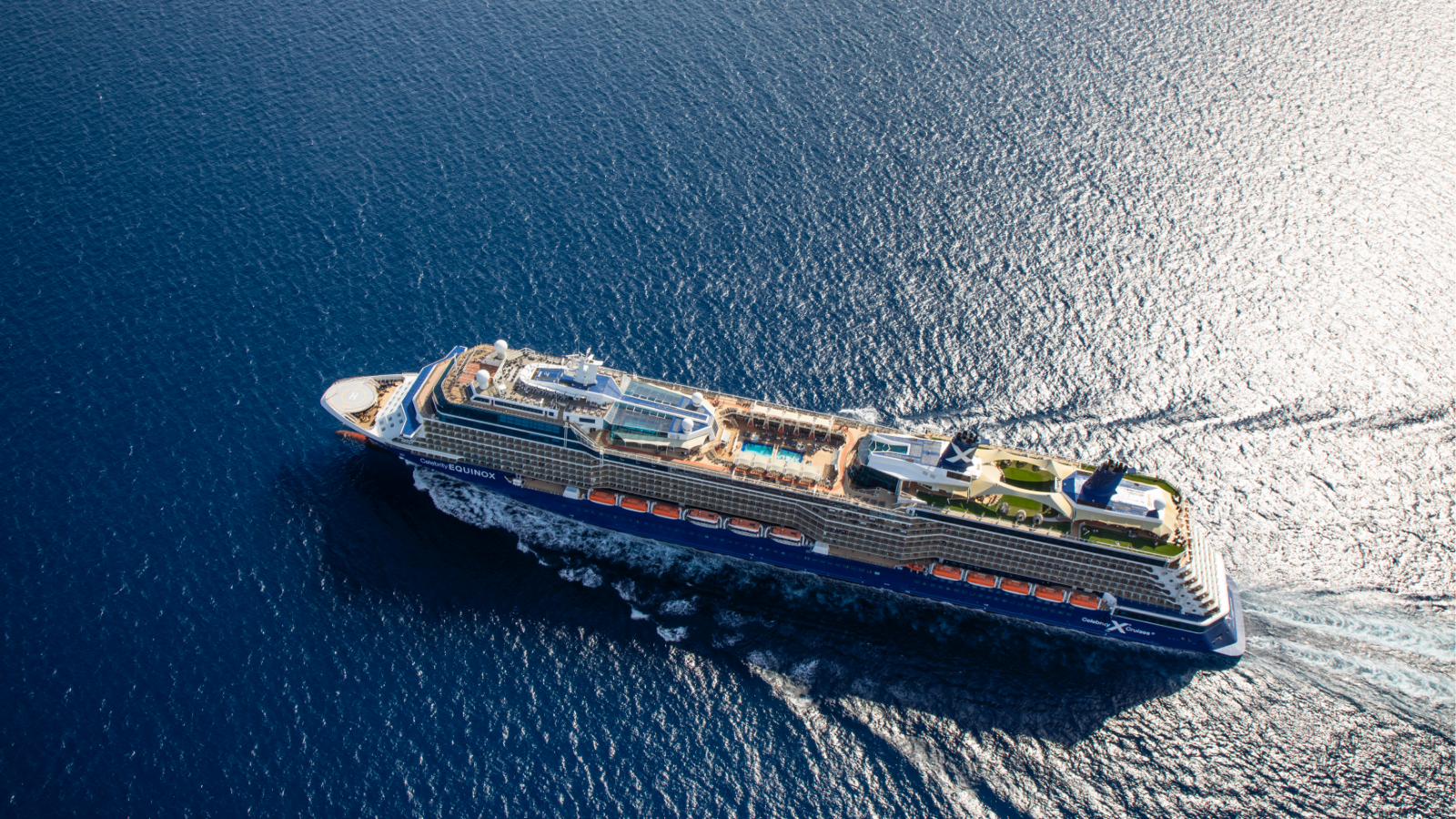 Aerial image of cruise ship Celebrity Equinox cruising in deep blue calm sea.