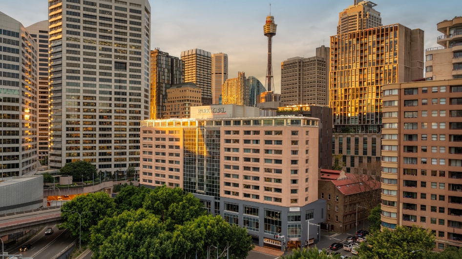 Aerial view of Parkroyal Darling Harbour hotel in Sydney. The hotel is castin the sunlight of the evening, set amongst the other buildings of the entertainment district.