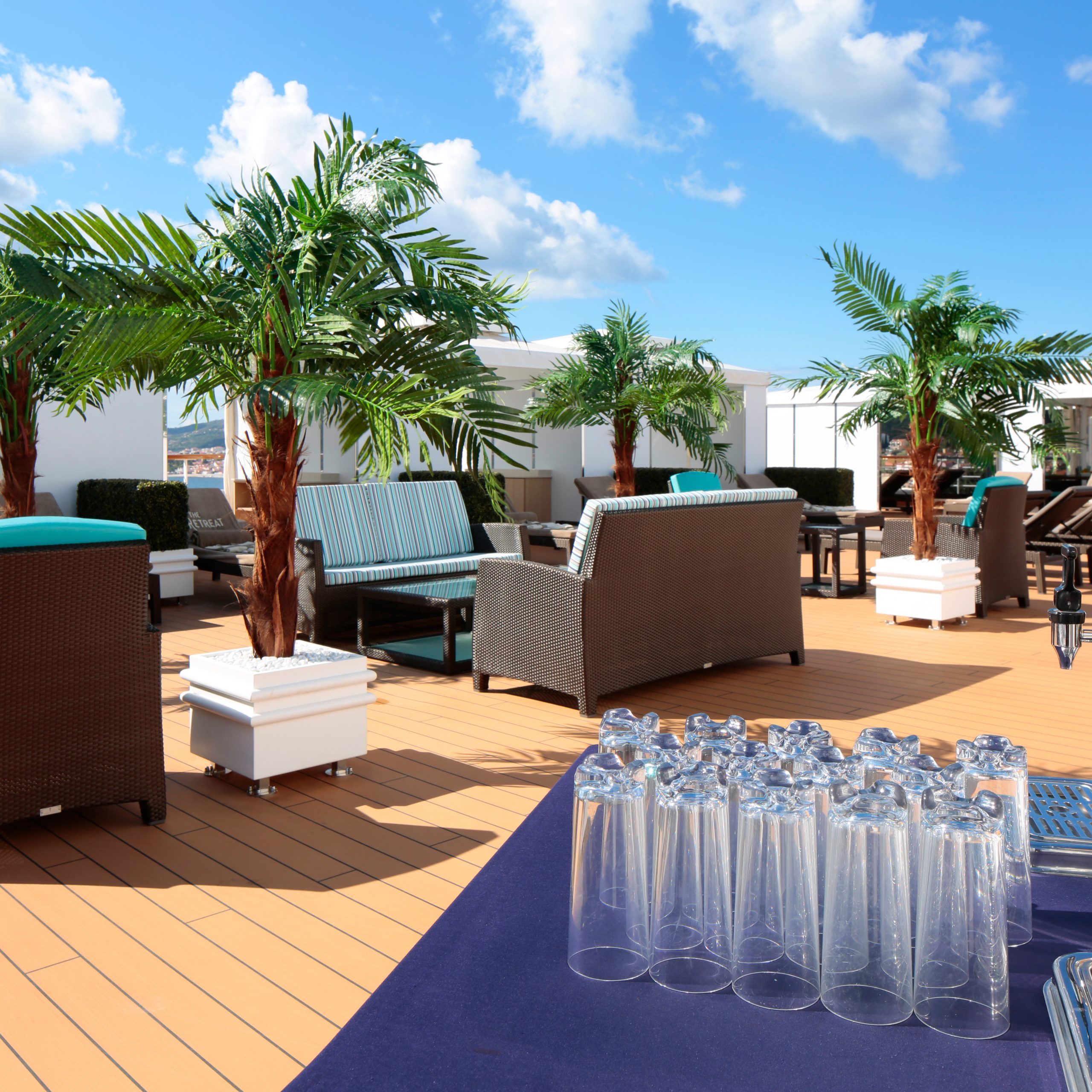 Relaxed seating area on deck of cruise ship Westerdam with refreshments, seating and palm trees.