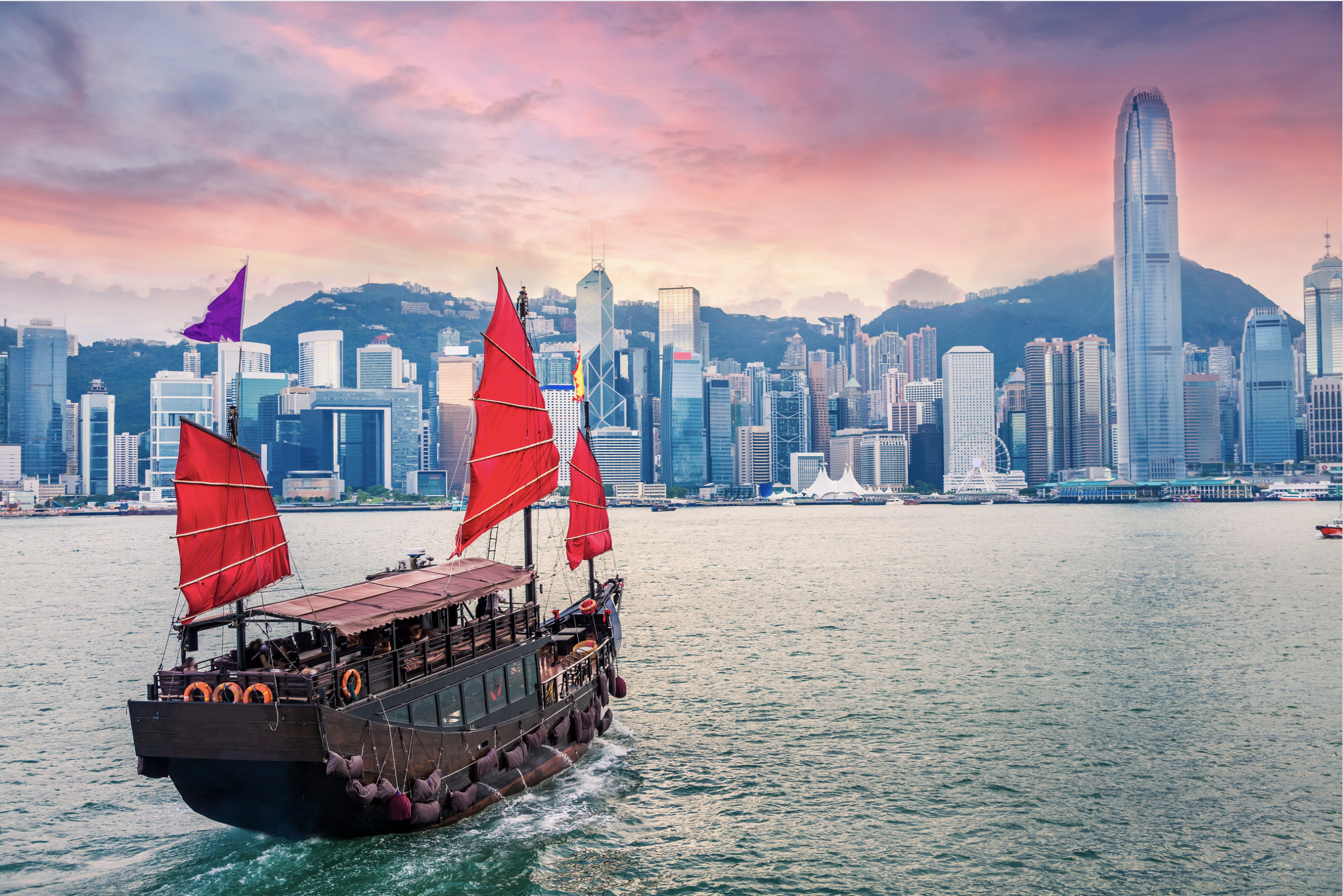 Traditional Junk boat sailing in to Victoria Harbour in Hong Kong at sunset.