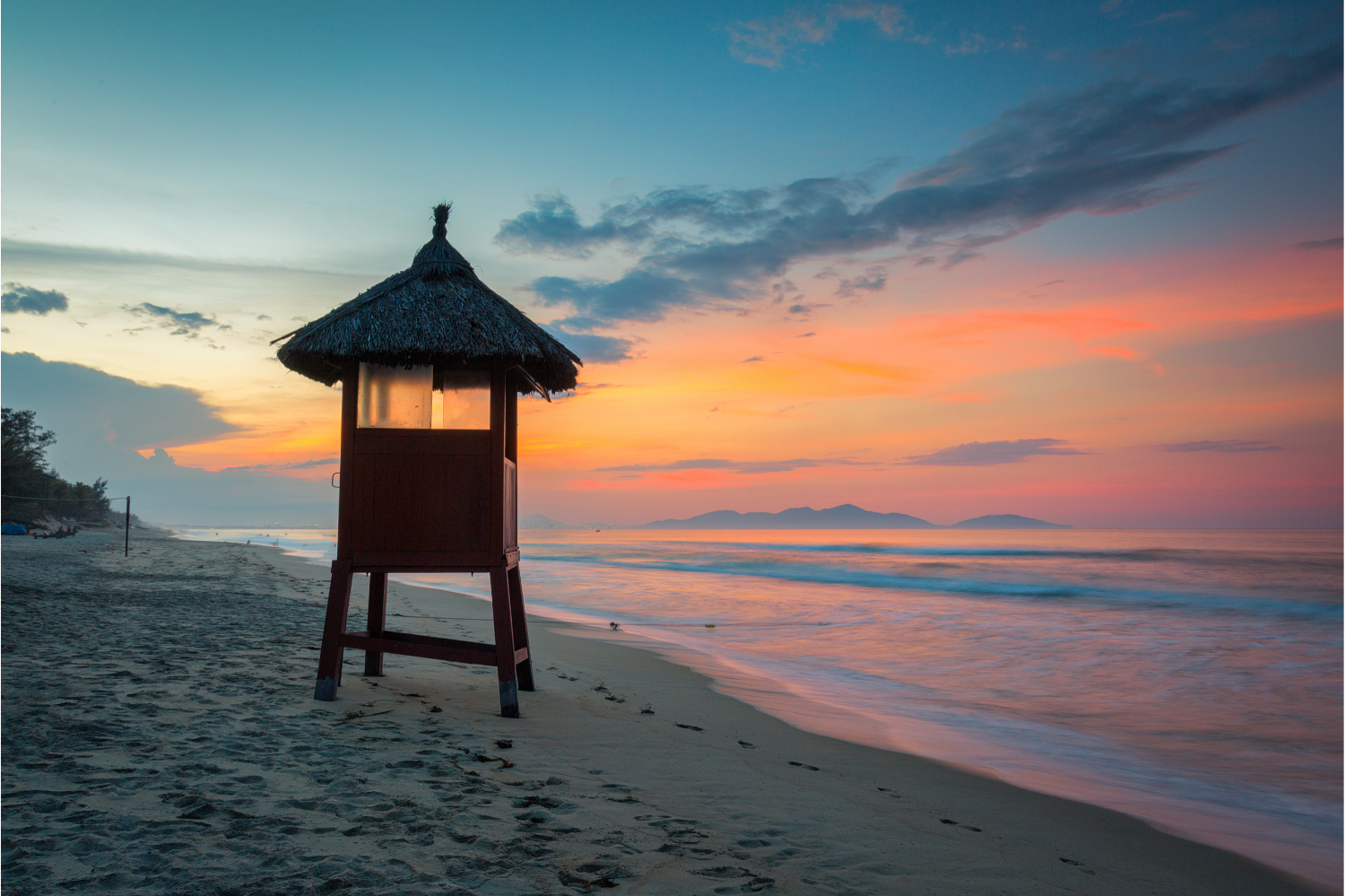 Lifeguard tower on a beach at dusk with pastel skies and gentle lapping waves