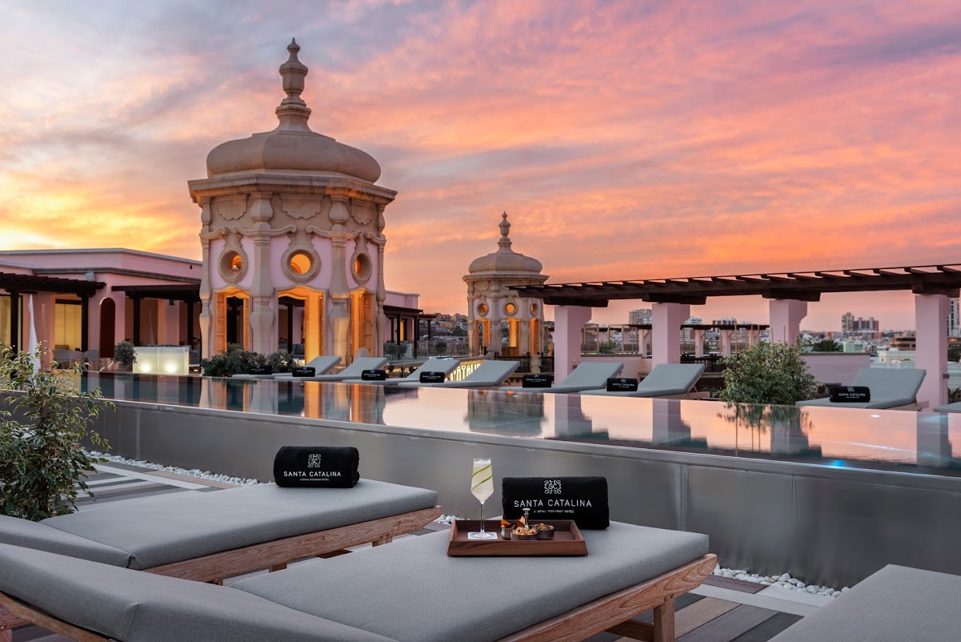 A vibrant sunset over Santa Catalina Hotel’s rooftop terrace, complete with sun loungers and domed architectural features.